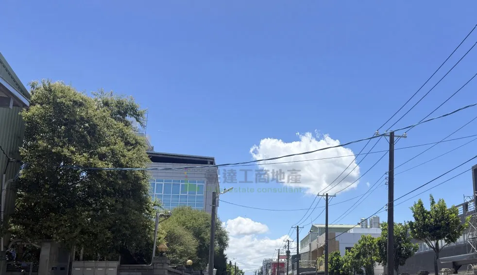 觀音崙坪一帶街景:晴天,道路兩側是既有的廠房與多層建築,電線桿與架空電線沿路配置