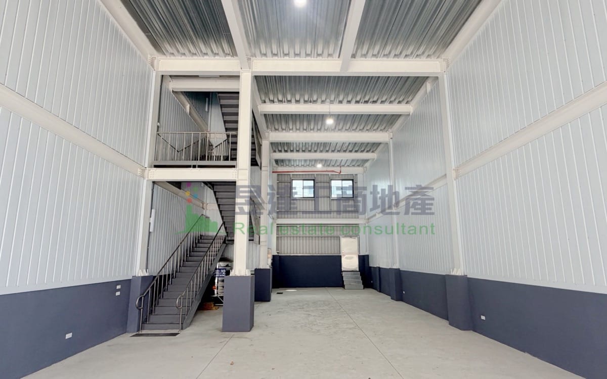 中壢鋼構兩層廠房一樓挑高空間實景：鋼骨樑柱，左側室內樓梯通往二樓