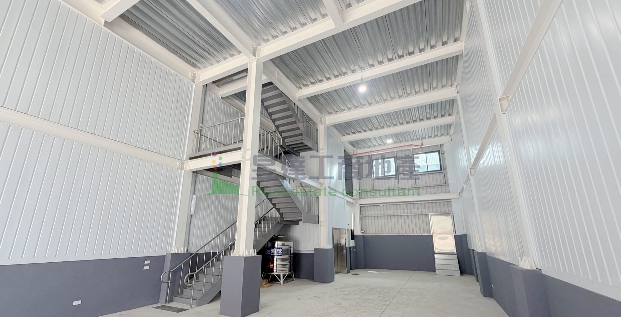 中壢丁建鋼構兩層廠房出售|一樓挑高 7.3 米、114 年完工、開價 5,280 萬 3 中壢鋼構兩層廠房一樓仰角實景:鋼骨結構與室內樓梯